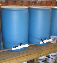 three large blue barrels sitting on top of a wooden shelf