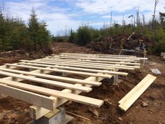 a large wooden structure is being built in the middle of some dirt and trees,