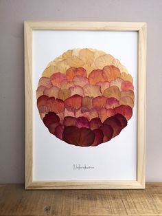 an art work with red and orange petals in a wooden frame on a shelf next to a wall