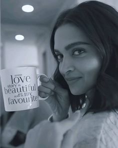 a woman holding a coffee mug in her right hand and looking at the camera with love on it