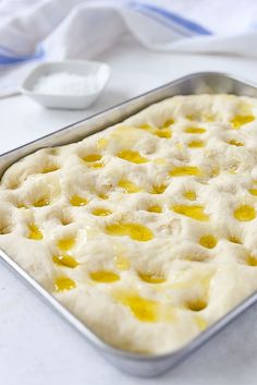 an uncooked pastry in a metal pan on a white tablecloth with a spoon