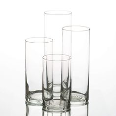 three clear glass vases sitting next to each other on a white surface with the bottom half empty