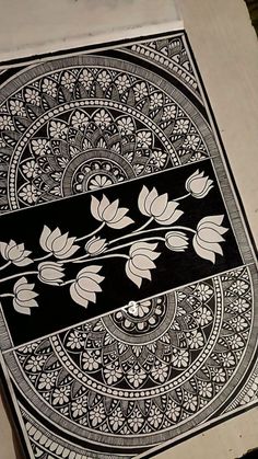an intricately designed piece of art is displayed on a table top, with flowers and leaves in the center