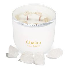 the chakra clear quartz candle is next to ice cubes on a white background