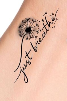 the word just breathe written in black ink on a woman's arm with a dandelion tattoo