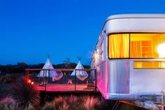 an rv is lit up at night with lights on the windows and inflatable hammocks