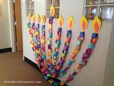 a bunch of candles that are made out of colored paper on a wall in an office