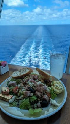 a plate full of food on the deck of a cruise ship with a glass of water