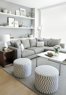 a living room filled with lots of furniture and white bookshelves on the wall