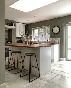 a kitchen with two stools next to an island and a clock on the wall