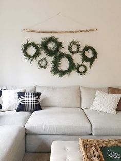 a living room with white couches and christmas wreaths on the wall above them