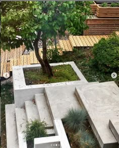 a concrete bench sitting under a tree in a garden