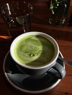 a cup filled with green liquid sitting on top of a saucer