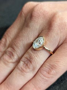 a woman's hand with a diamond ring on top of her finger and the other hand holding an engagement ring