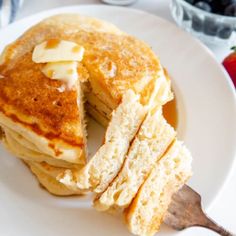 a stack of pancakes with butter and syrup on top, sitting on a white plate