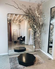 a large mirror sitting in the middle of a room next to a black coffee table