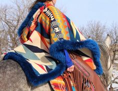 a native american woman riding on the back of a gray horse in winter clothing and fur