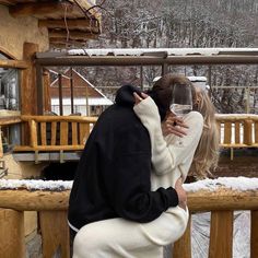 a man and woman kissing while holding a glass of wine in front of snow covered mountains