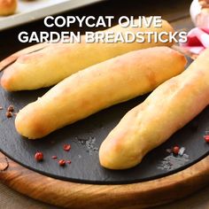 two long breadsticks sitting on top of a black plate next to another one