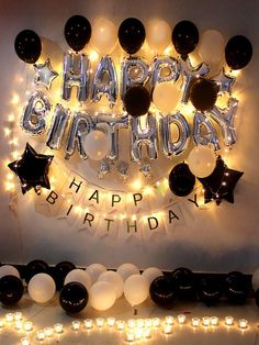 a birthday party with black and white balloons, lights and streamers on the wall