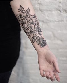 a woman's arm with flowers on it and her hand holding the wrist tattoo