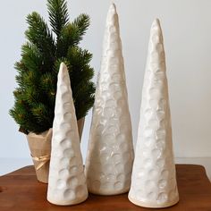 three white ceramic trees sitting on top of a wooden table