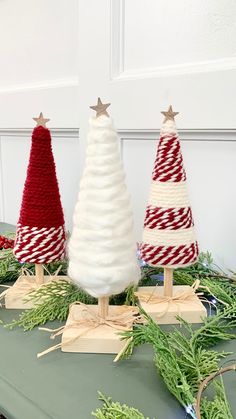 three knitted christmas trees sitting on top of a table