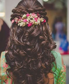 the back of a woman's head with flowers in her hair and long curls