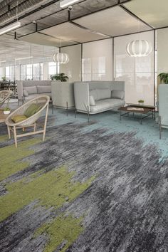 an office with chairs, couches and rugs in front of large windows on the wall