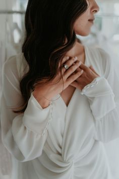 a woman wearing a white shirt and holding her hands to her chest