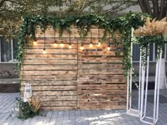 a wooden fence with lights hanging from it's sides and some plants growing on the side