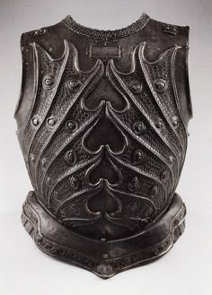 an old metal shield with intricate designs on the front and sides, sitting on a white surface