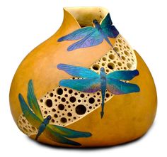 a yellow vase with dragonflies painted on it's side and holes in the bottom