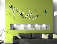 a living room with green walls and white flowers on the wall, birds flying around