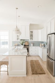 a clean kitchen with white cabinets and stainless steel appliances, along with an area rug that matches the hardwood flooring