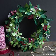 a wreath is sitting on a table next to some spools of twine