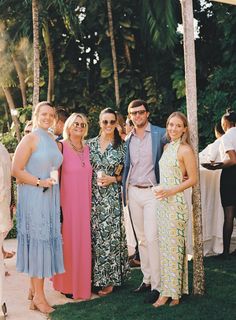 a group of people standing next to each other on a lush green field with palm trees