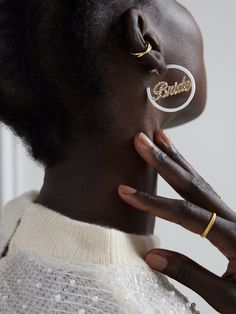 a close up of a person wearing earring rings and holding their hand to her ear