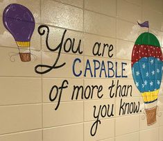 a sign on the wall that says you are capable of more than you know with hot air balloons