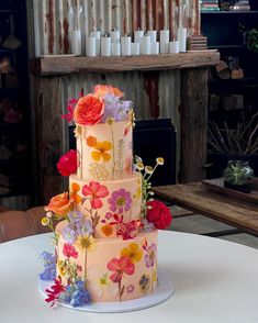 a multi - tiered cake with colorful flowers on the top is sitting on a table