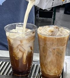 two drinks are being poured into plastic cups