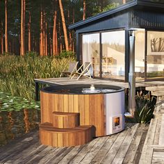 a hot tub sitting on top of a wooden deck next to a small building and water