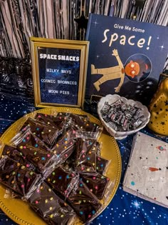 a table topped with lots of chocolate covered pieces of cake next to a sign that says space snacks