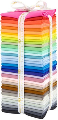 a stack of different colored papers with white ribbons