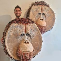 a man standing next to two masks made out of straws and other things that are hanging on the wall