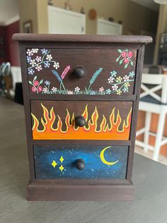 a wooden cabinet with painted flames and stars on it's sides, sitting on a table