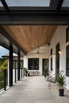 an outdoor covered porch with chairs and potted plants