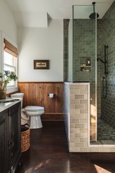 a bathroom with a toilet, sink and shower in it's center wall next to a window