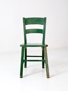 a green wooden chair sitting on top of a white floor