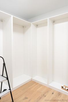 an empty room with white walls and wooden floors, including a stepladder in the foreground